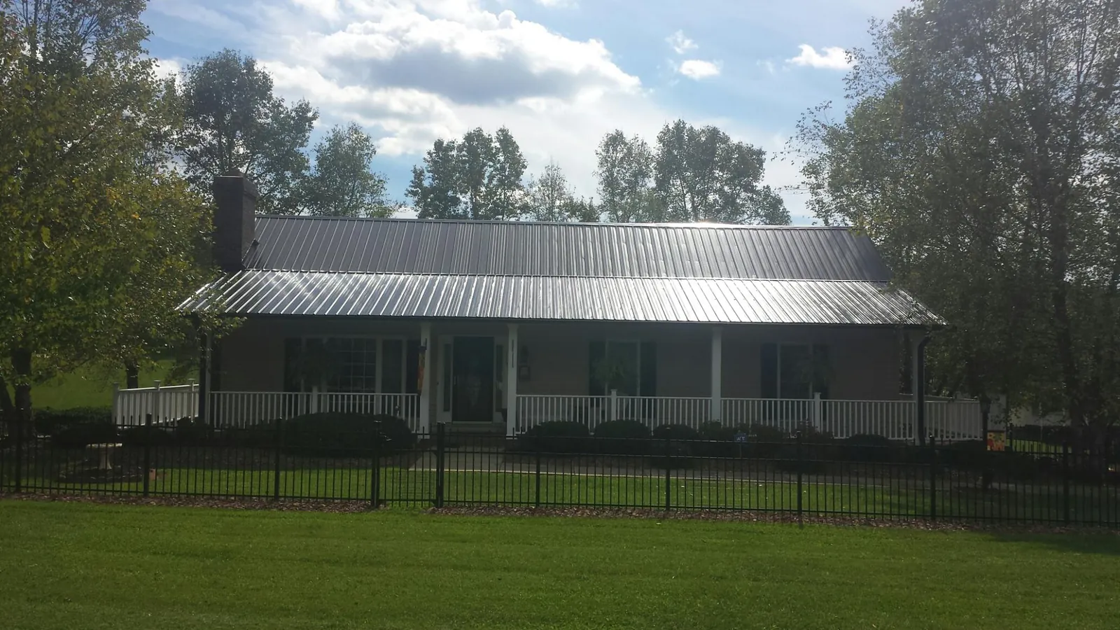 Gray metal roof on a brick ranch with a full width front porch — Gutter Guard Installation work by our crew in Lakeland