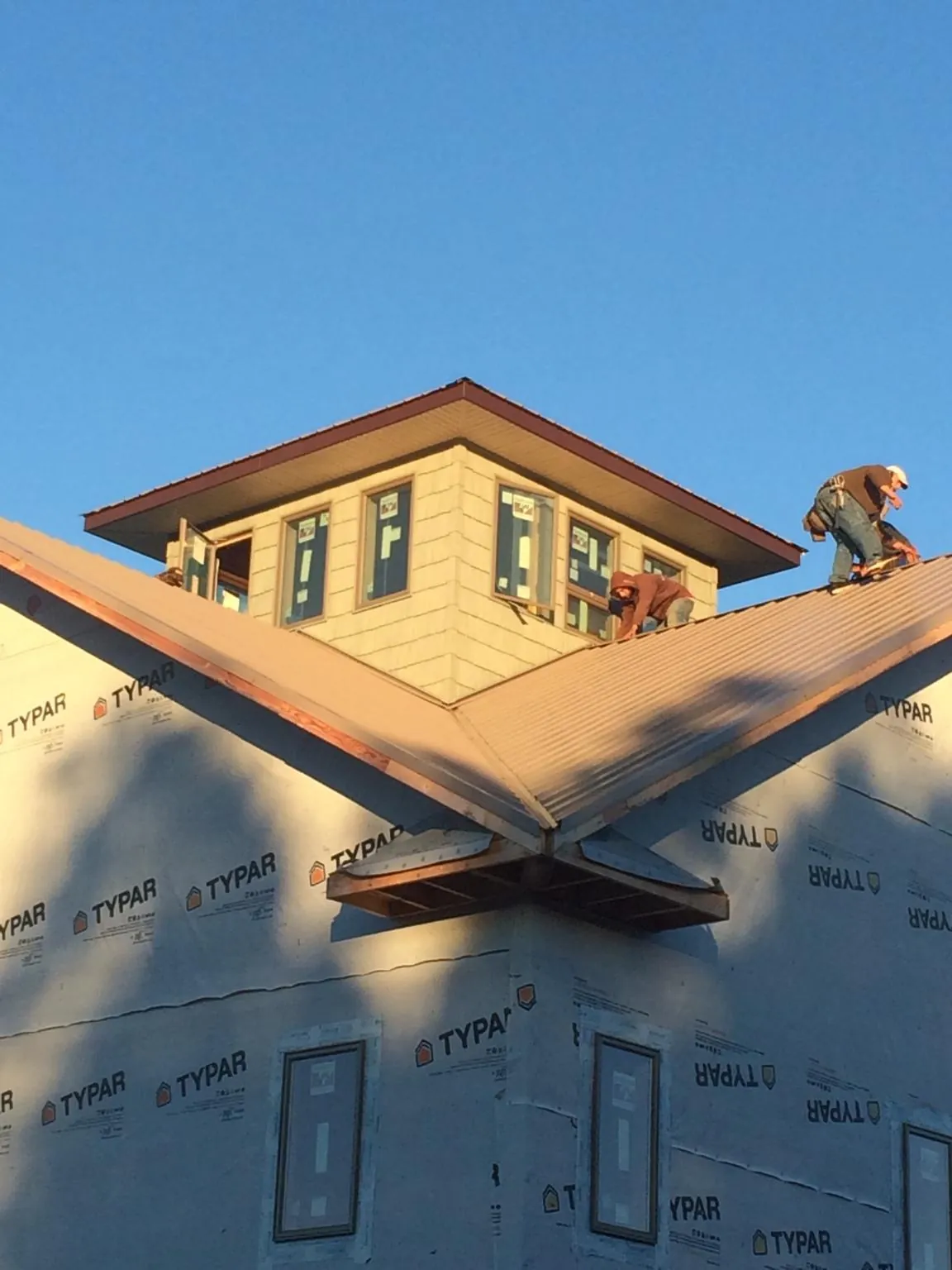 Roofers working around a rooftop cupola on a new metal roof at sunset — Roof Waterproofing in Lakeland by Roofing Brothers